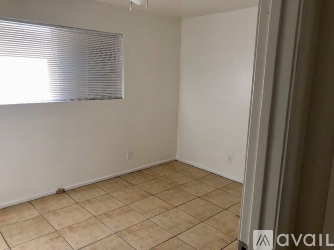 A room with tiled flooring and a window with blinds.