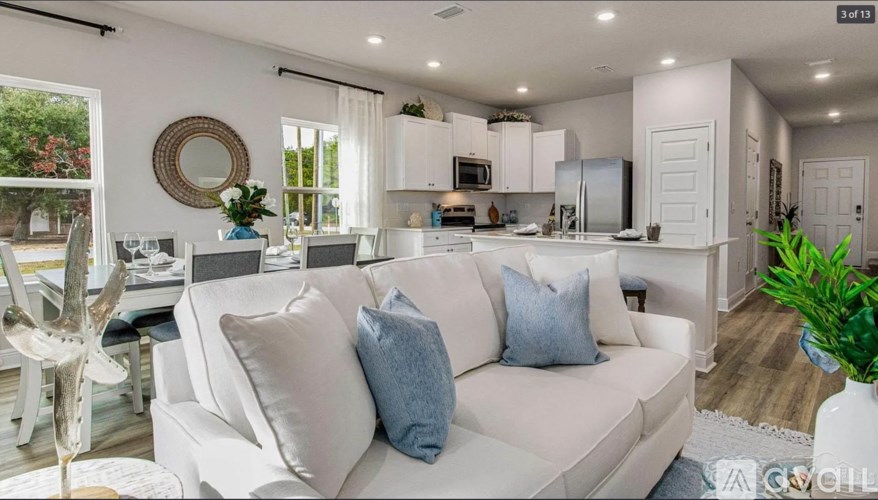 A white couch with blue pillows is in the middle of a brightly lit room.