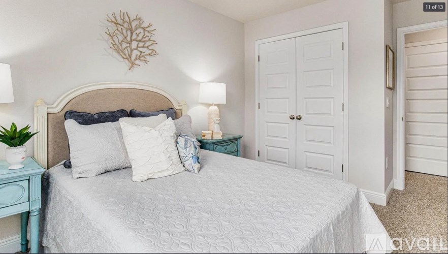 A bedroom with a bed, nightstand, and a wall decoration.