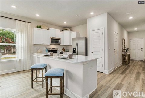 A kitchen with white cabinets and a bar area with blue stools.