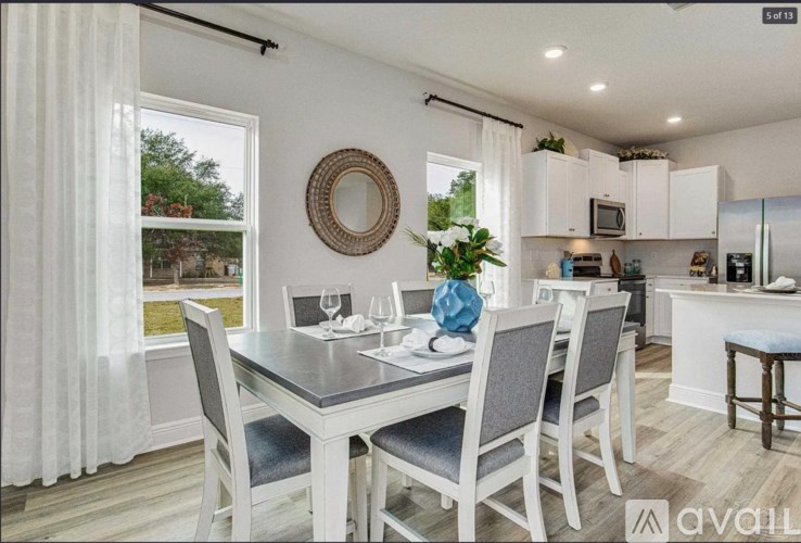 A dining room with a table set for two and a view of a backyard.