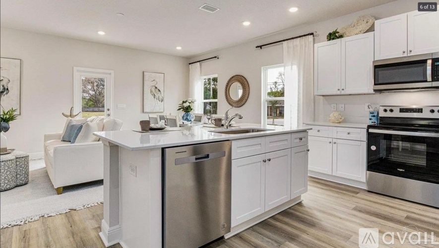 A modern kitchen with white cabinets and stainless steel appliances.