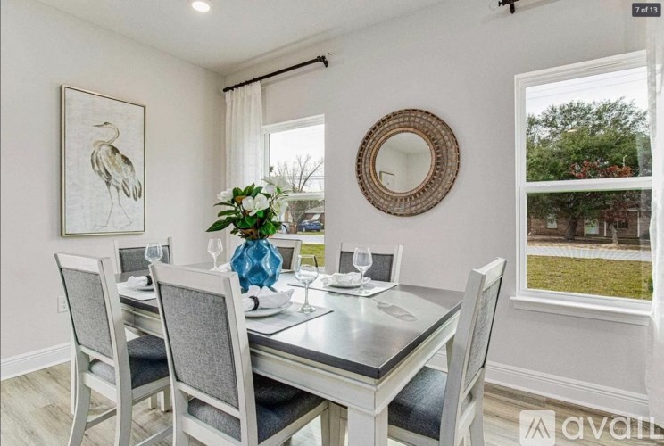 A dining room with a table set for two and a view of the backyard.
