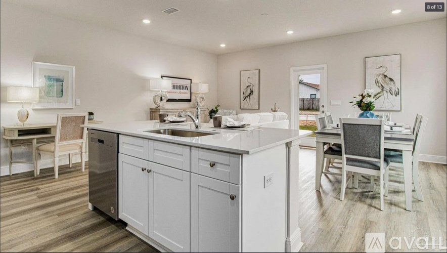 A modern kitchen with white cabinets and a wooden floor.