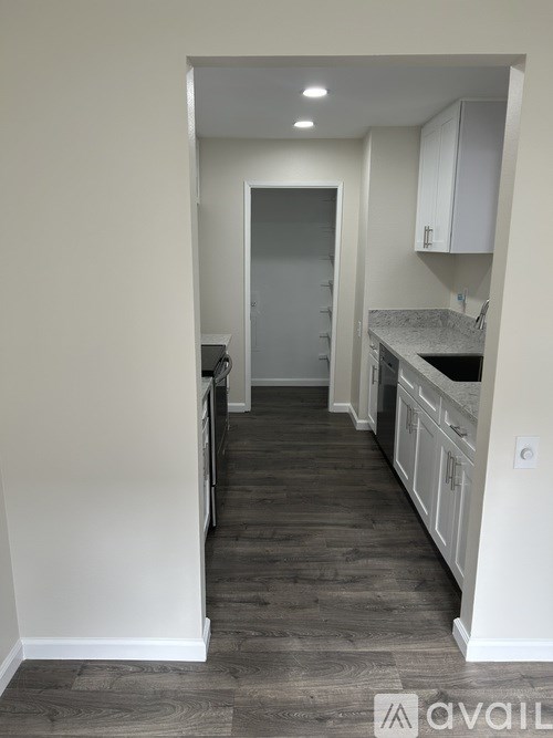 A kitchen with white cabinets and a grey door.
