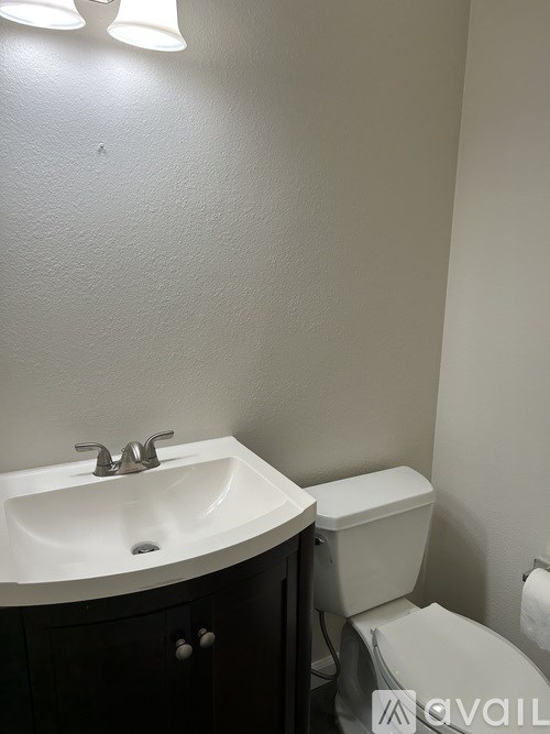 A white sink with a silver faucet and a toilet in a bathroom.