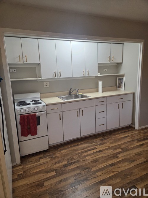 A kitchen with white cabinets and a wooden floor.