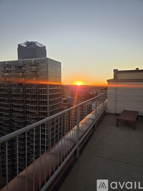 A sunset view from a balcony with a table and chairs.