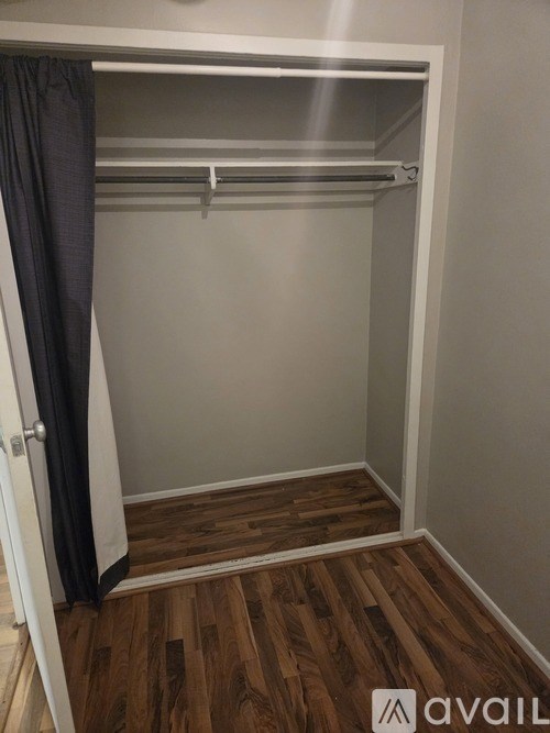 A walk-in closet with a wooden floor and white walls.