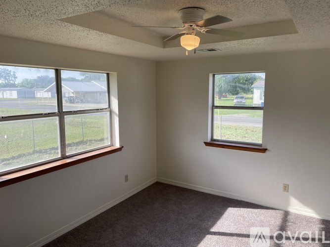 A room with a ceiling fan and two windows.