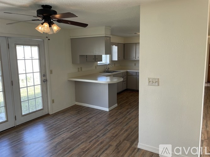 A kitchen with a ceiling fan and wooden floors.