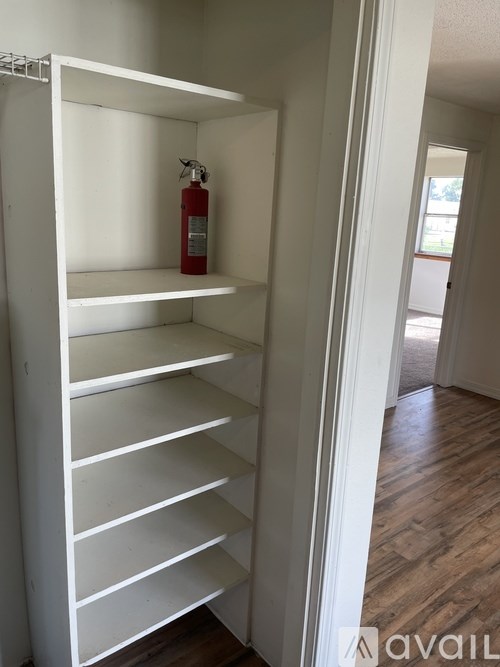 A white shelving unit with a fire extinguisher on the top shelf.