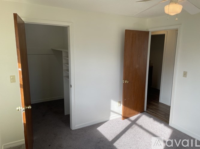 A room with a ceiling fan and two doors, one of which is open.