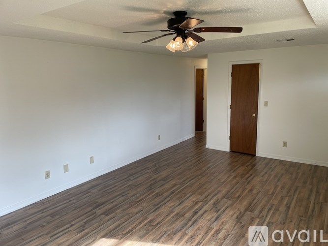 A room with a ceiling fan and wooden flooring.