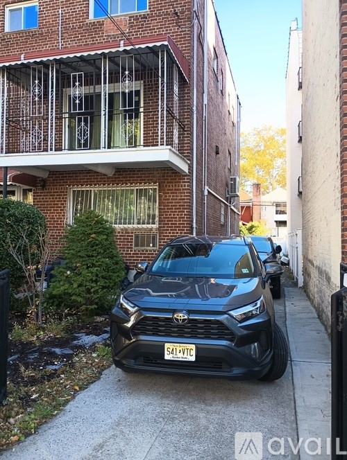 A black Toyota SUV is parked on a sidewalk in front of a brick building.