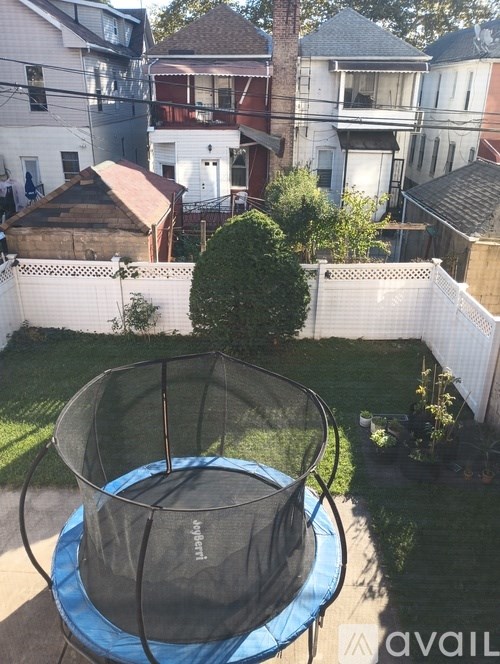 A trampoline in a backyard surrounded by a white fence.