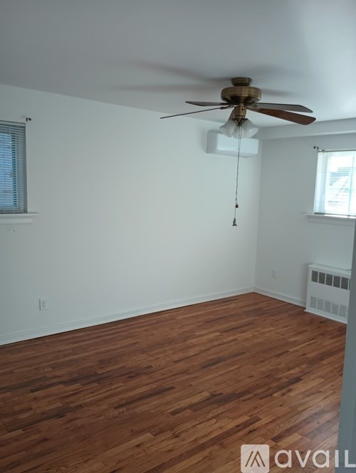 A room with a ceiling fan and wooden flooring.