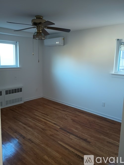 A room with a ceiling fan and wooden flooring.