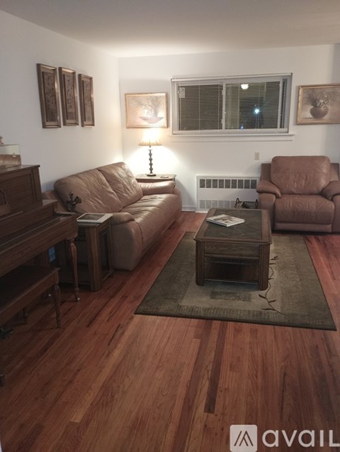 A living room with brown leather furniture and a wooden floor.