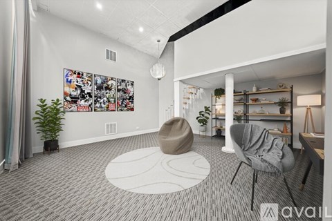 A living room with a grey carpet and a white rug.