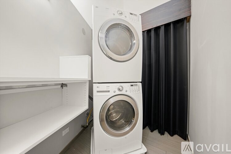 A white washing machine is stacked on top of a white dryer in a small laundry room.
