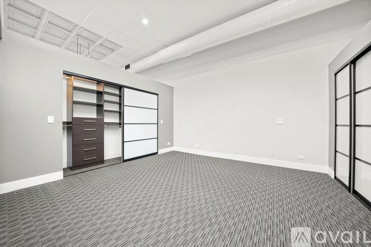 A spacious room with a grey carpet and a wooden cabinet.