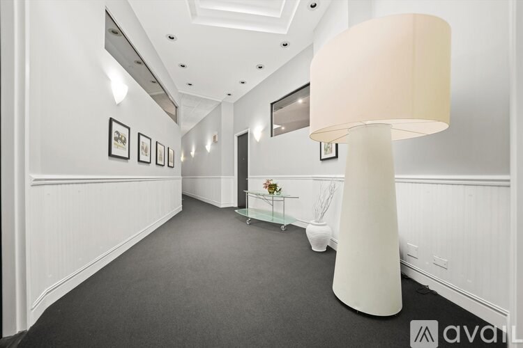 A white floor lamp stands in a hallway with a grey carpet.