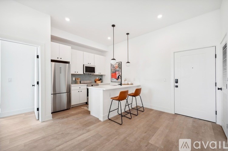 A kitchen with a white island and bar stools.