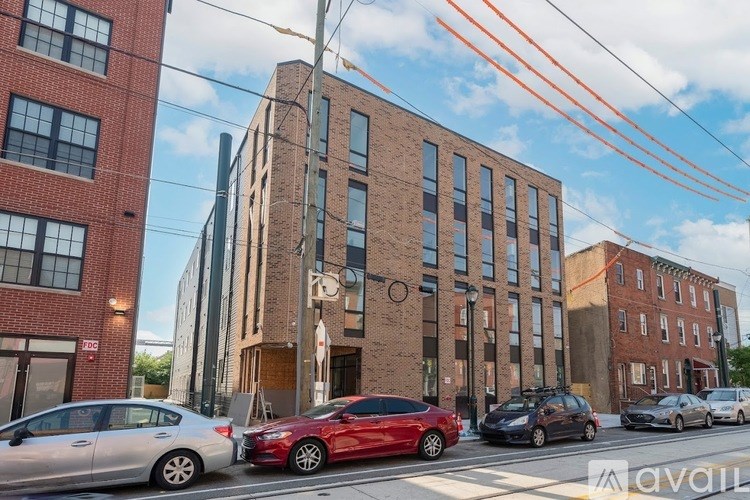 A red car is parked on the side of a street in front of a building.