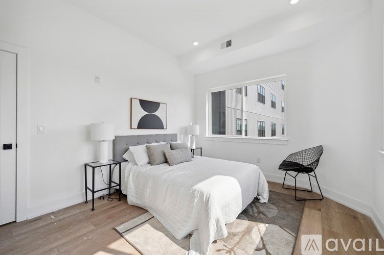 A bedroom with a large bed, a chair, and a painting on the wall.