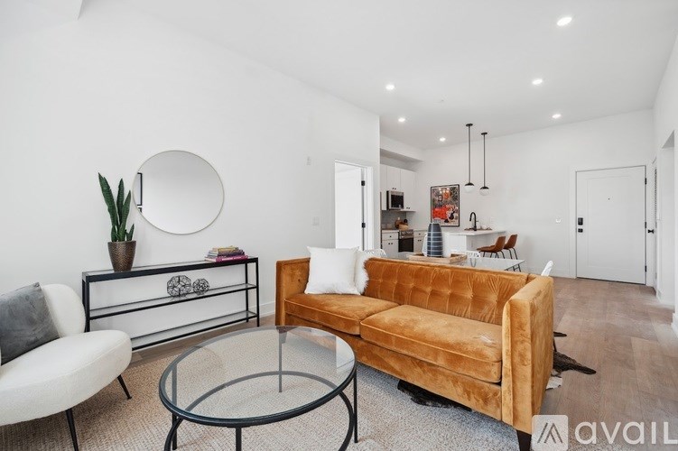 A living room with a brown couch, a glass table, and a white chair.