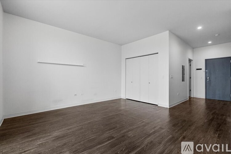 A spacious room with wooden flooring and white walls.