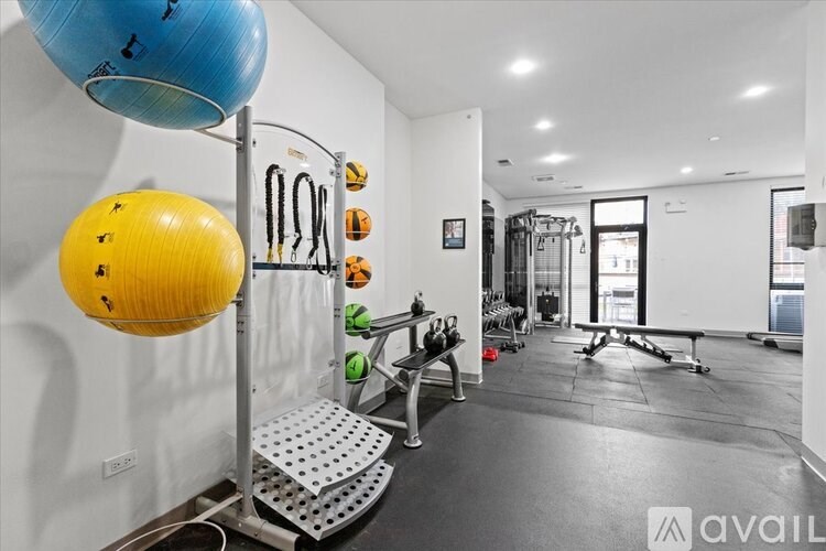 A gym with a blue and yellow ball hanging from a rack, a bench, and various exercise equipment.