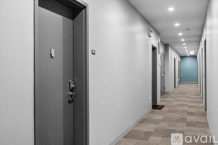 A hallway with a door on the left and a blue door at the end.