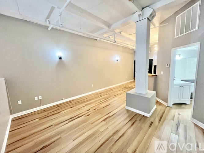 A spacious room with wooden flooring and white walls.