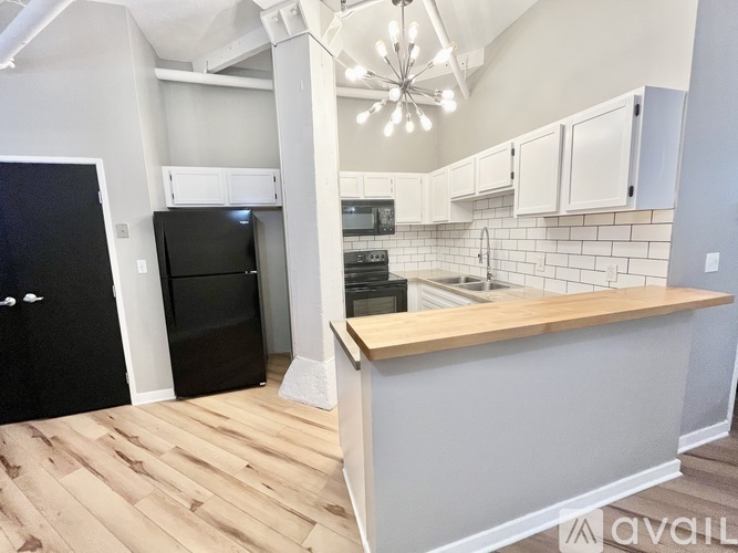 A kitchen with a black refrigerator and wooden floors.