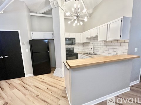 A kitchen with a black refrigerator and wooden floors.