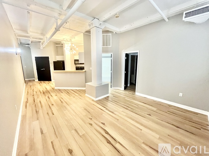 A spacious room with wooden flooring and white walls.