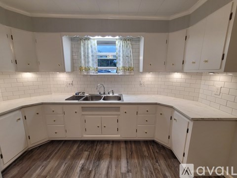 A kitchen with white cabinets and a wooden floor.