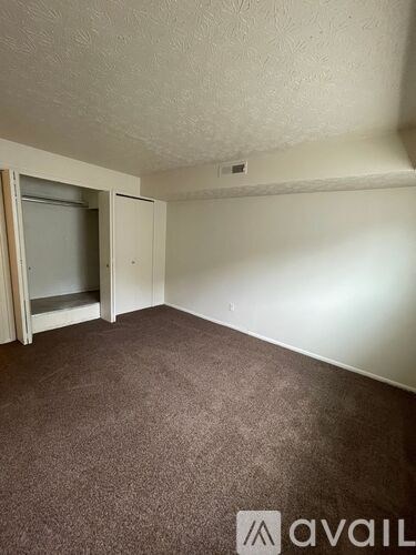 A carpeted room with a door and a window.