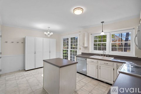 A kitchen with white cabinets and a brown island.