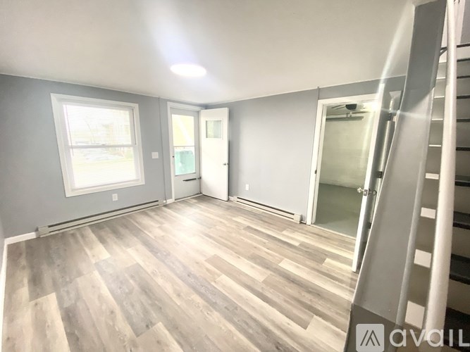 A room with wooden flooring and a staircase on the right side.