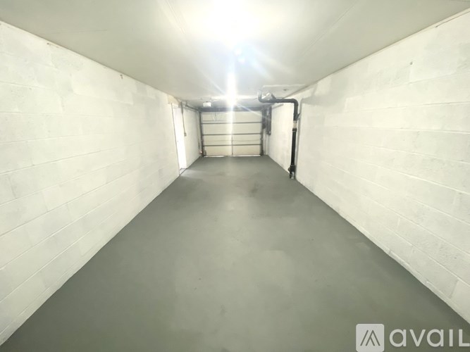 A long, narrow, white-walled room with a light source at the end.