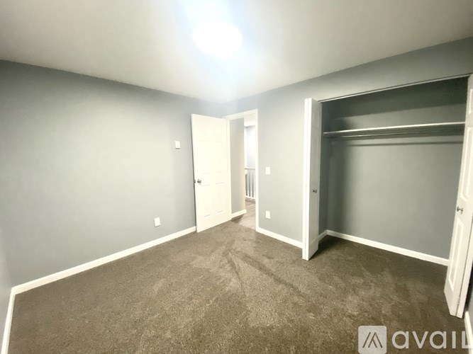 A room with grey walls and carpeted floor with a white door and a white closet door.