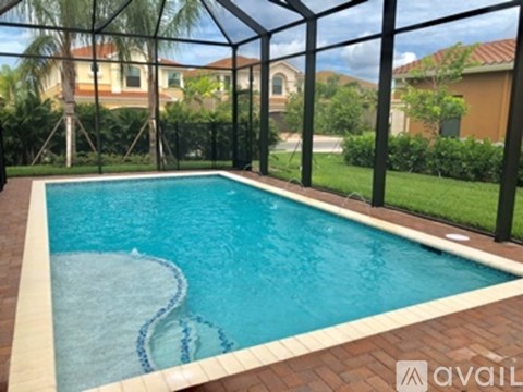 A pool surrounded by a black fence with a house in the background.