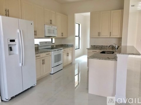 A kitchen with white appliances and a marble countertop.