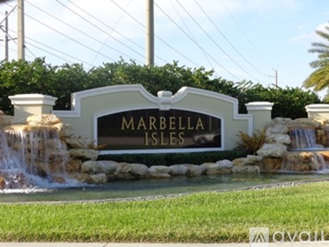 A sign that says Marbella Isles in front of a waterfall.