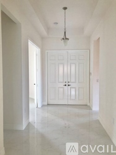 A hallway with a white door and a chandelier hanging from the ceiling.