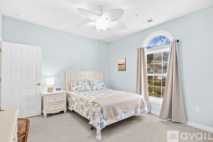 A bedroom with a large bed, a dresser, and a window with curtains.