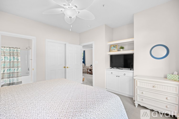 A bedroom with a large bed, a television, and a window with curtains.